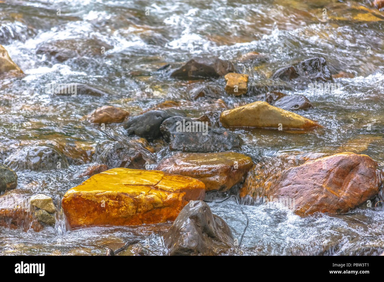 Orange rock among the creek bed Stock Photo