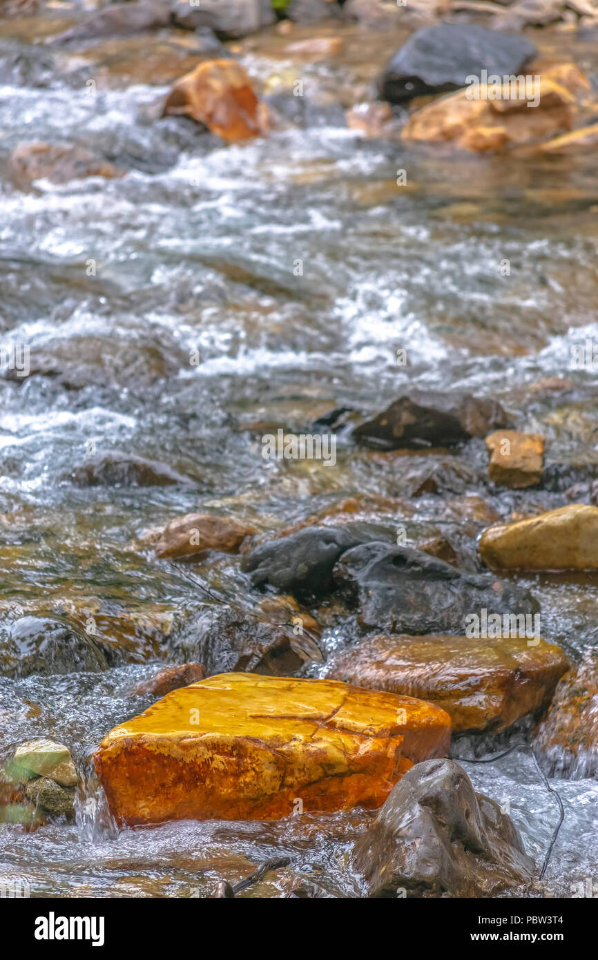 Orange rock among the wet creek bed Stock Photo