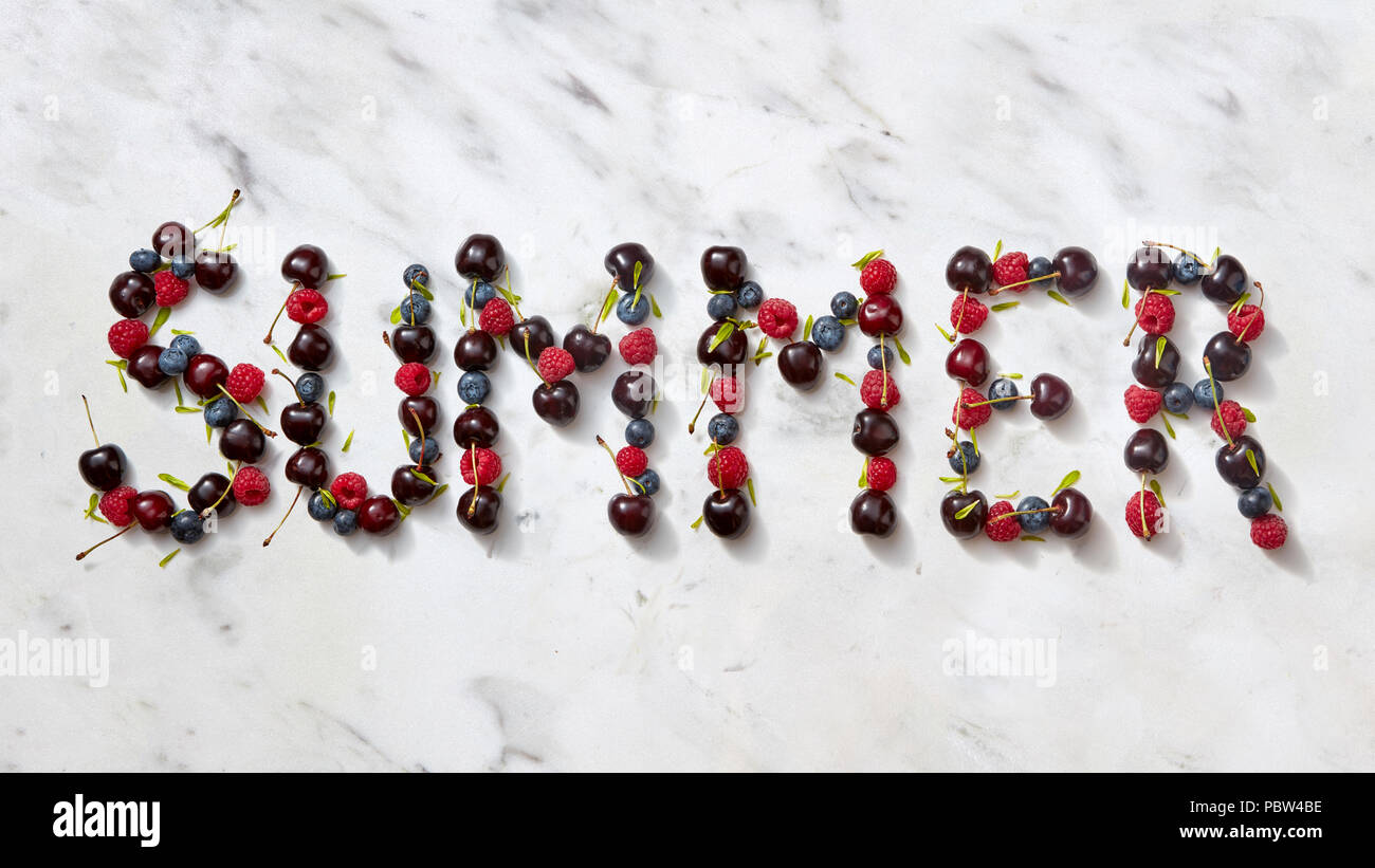 Summer background with summer berries - word "SUMMER" from cherry, raspberry, blueberries on gray stone background. Stock Photo