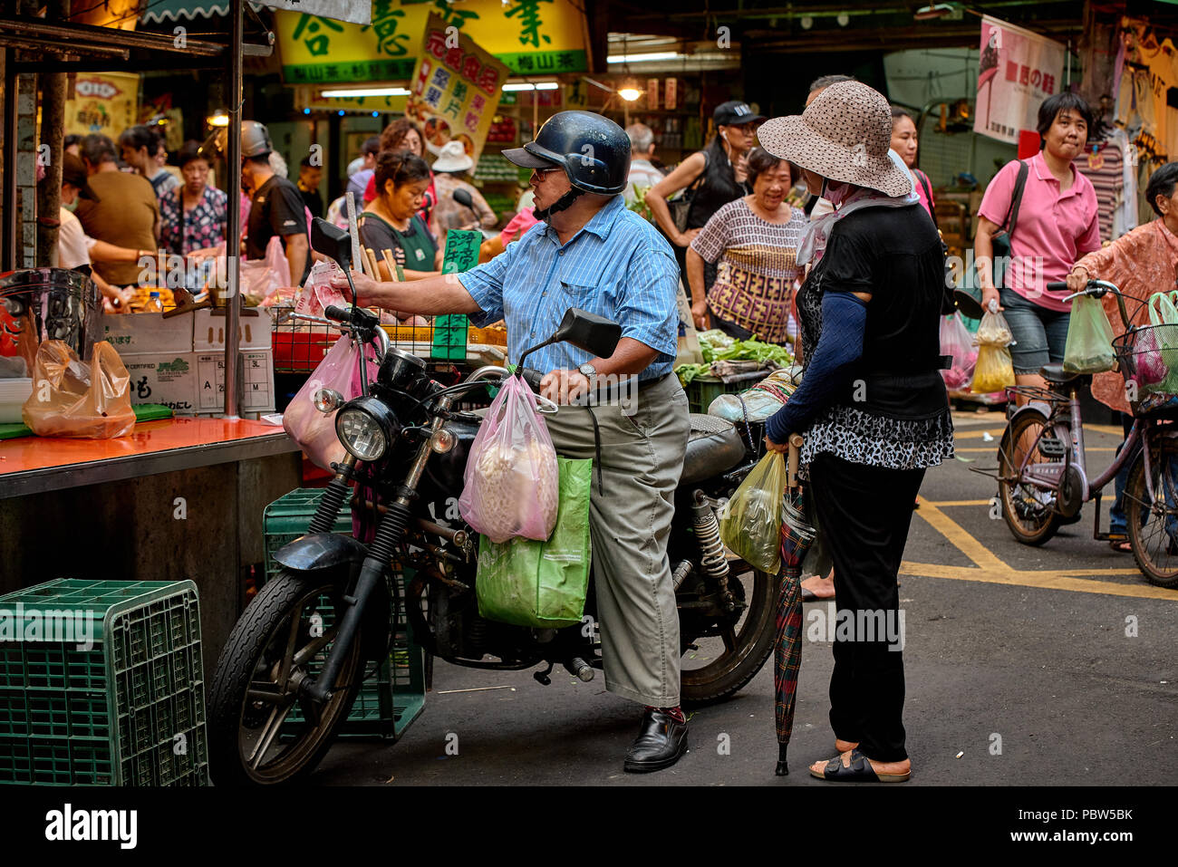 Asian elderly man on the old bike choose food from street vendor Stock Photo