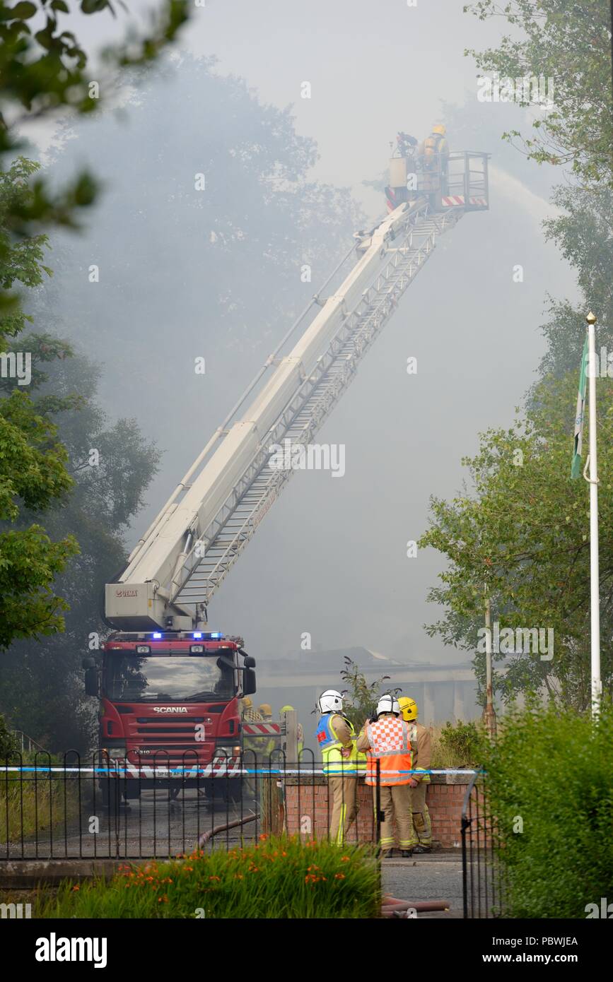 Glasgow, UK. 30th July, 2018. Glasgow, Scotland, UK. A large fire forces the closure of Crookston Rd in Glasgow as fire appliances line the street and firefighters use breathing apparatus and high reach platforms to tackle the blaze. Stock Photo