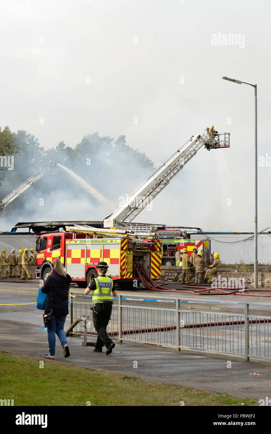 Glasgow, UK. 30th July, 2018. Glasgow, Scotland, UK. A large fire forces the closure of Crookston Rd in Glasgow as fire appliances line the street and firefighters use breathing apparatus and high reach platforms to tackle the blaze. Credit: Douglas Carr/Alamy Live News Stock Photo