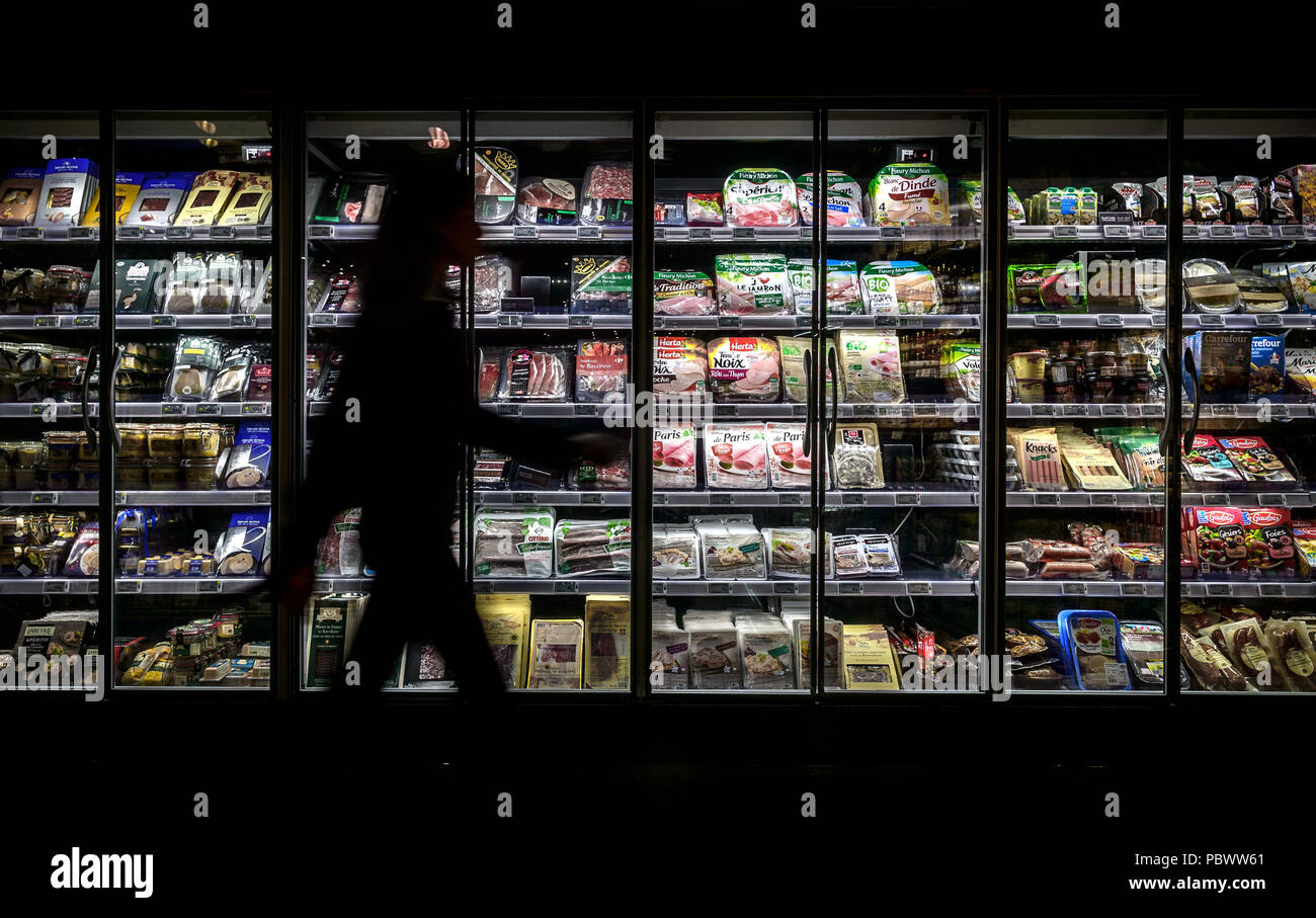 Berlin, Germany. 11th July, 2018. A woman passes the refrigerated counter with meat products in a supermarket. On average, every German eats almost 60 kilograms of meat a year. But only a small part of the whole animal is actually consumed. Credit: Sina Schuldt/dpa/Alamy Live News Stock Photo