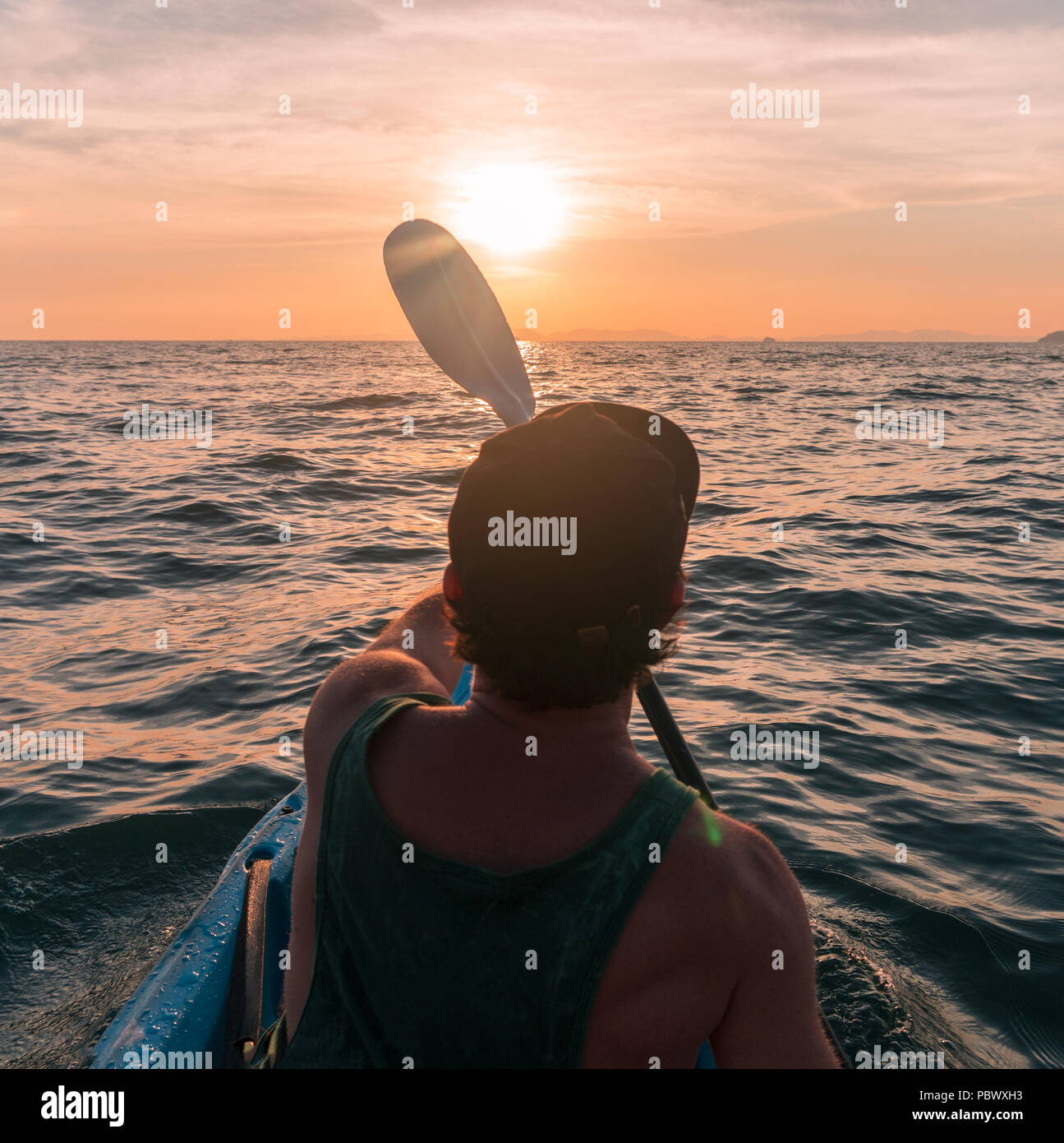 Kayaking. Man With kayak paddle at sunset sea Rowing to the Sun. Stock Photo