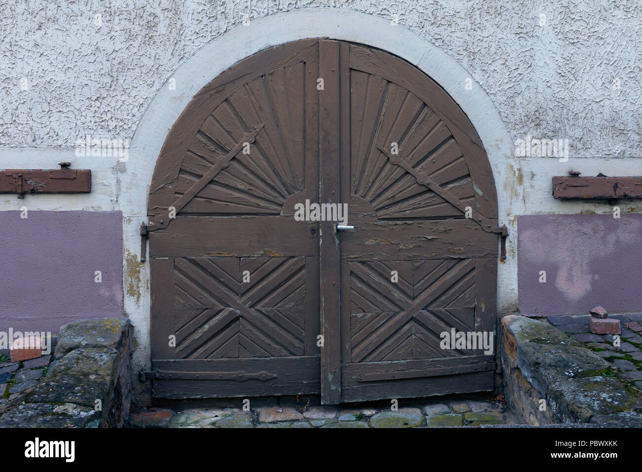 The old wooden doors, decorated with metal ornaments, are typical for the historical part of small German cities. Old wooden door close-up Stock Photo