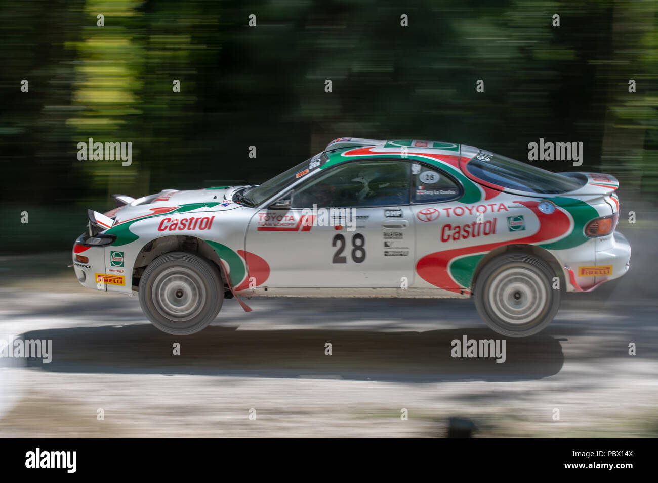 A Toyota Celica GT-Four ST185 rally car leaps through the air while racing through the forest rally stages at the Goodwood Festival of Speed 2018 Stock Photo