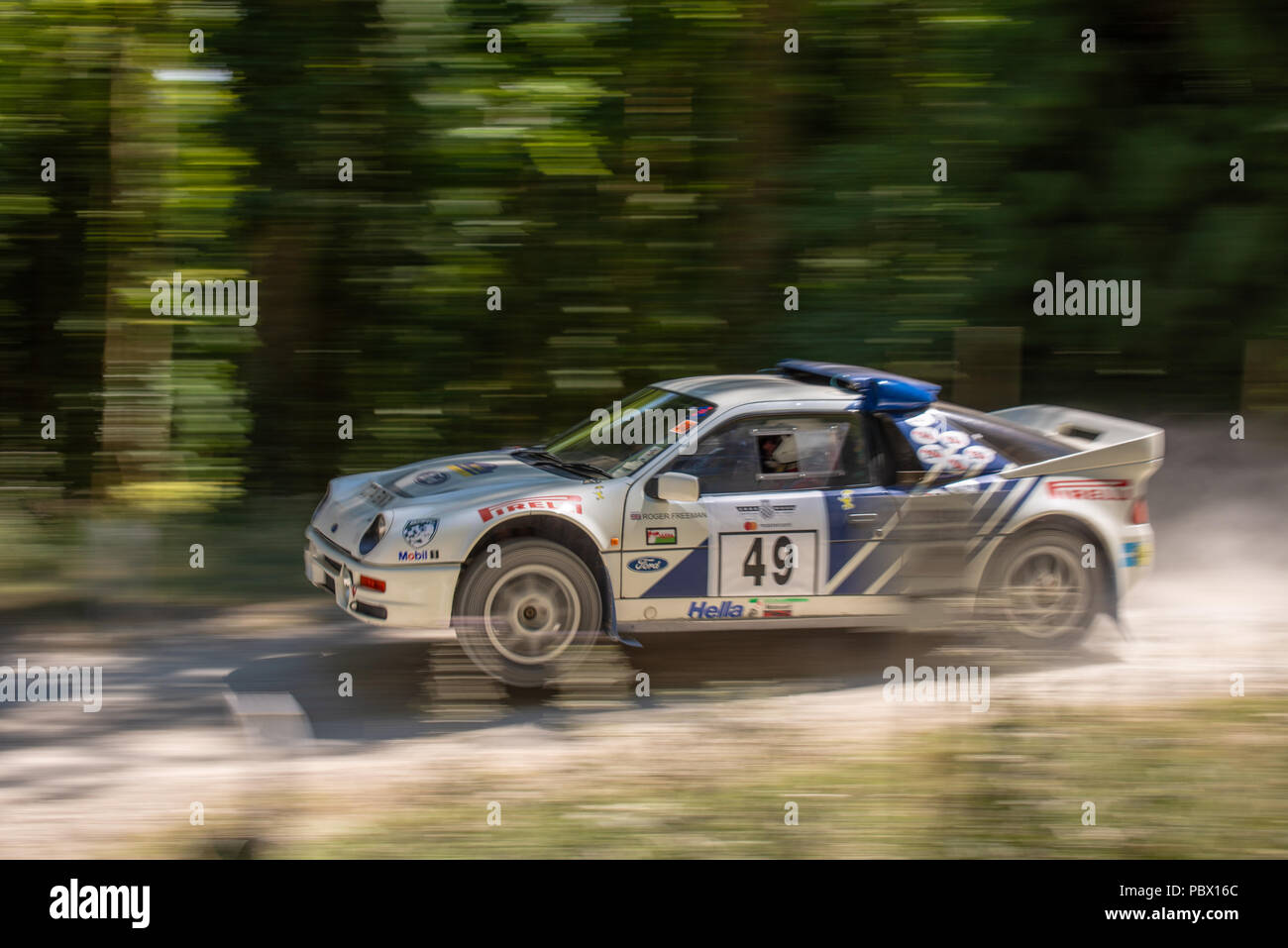 A Ford RS200 rally car lifts the front wheels as it leaves the jump on the forest rally stages at the Goodwood Festival of Speed 2018 Stock Photo