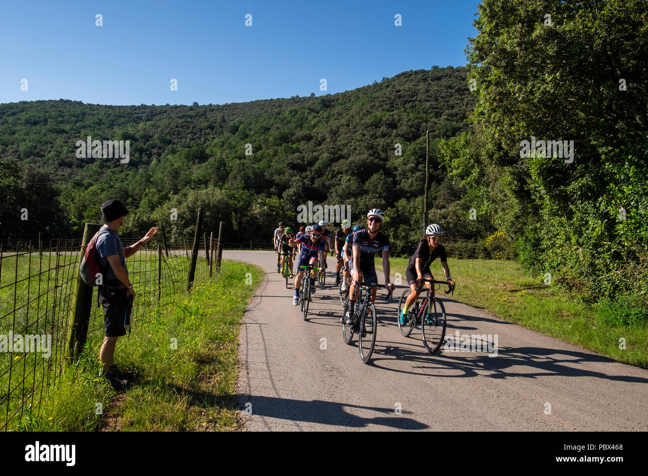 Cyclists passing a hiker on the GI524 at El Sallent in Catalonia, Spain Stock Photo