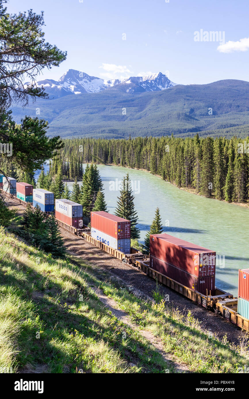 A freight train on the Canadian Pacific Railway running beside the Bow River and Rocky Mountains at Castle Junction NW of Banff, Alberta, Canada Stock Photo