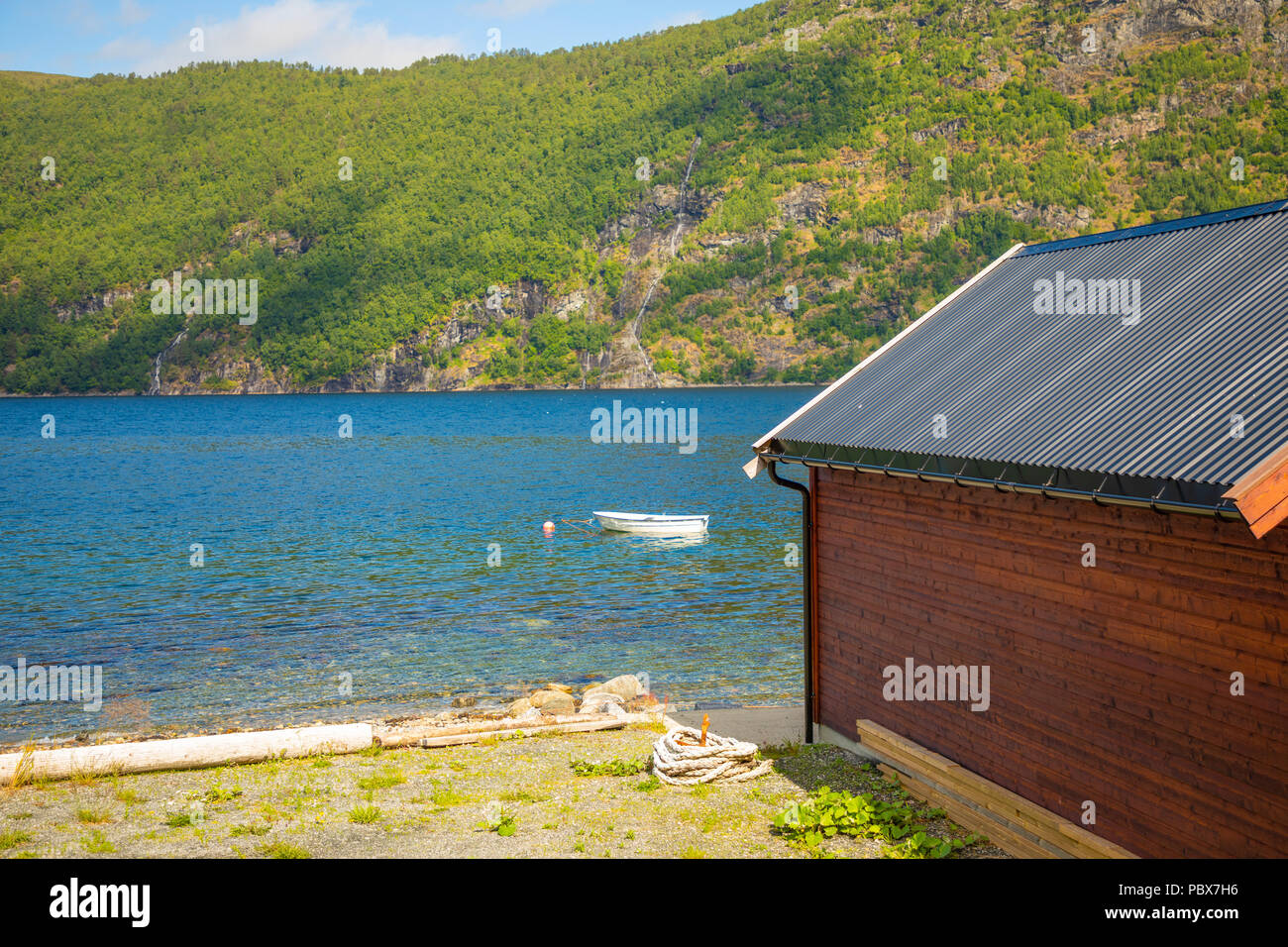Typical norwegian wooden rorbu hut on the fjord beach in sunny summer day in Norway Stock Photo