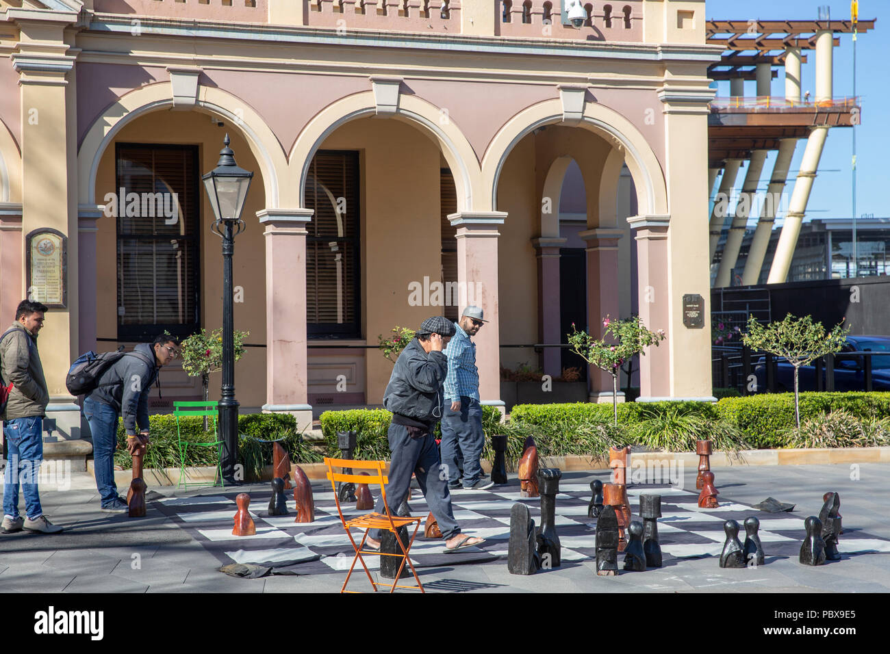Asian men playing street chess outside Parramatta town hall in centenary square,Western Sydney,Australia Stock Photo