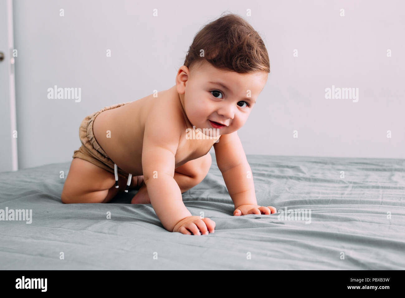 Beautiful baby crawling on the bed in the room, family lifestyle Stock Photo