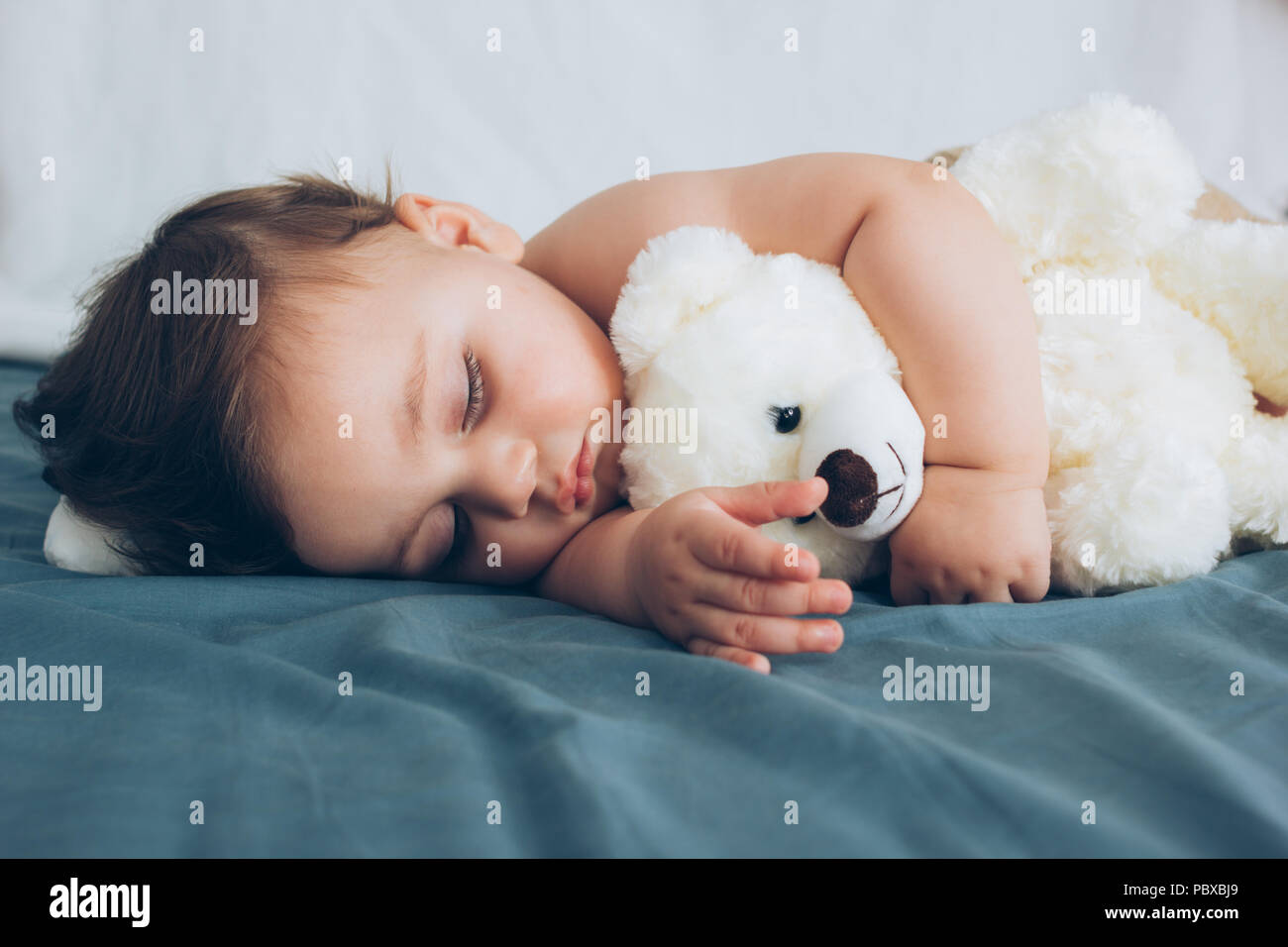 Beautiful baby sleeping with his teddy bear aside, family concept Stock Photo
