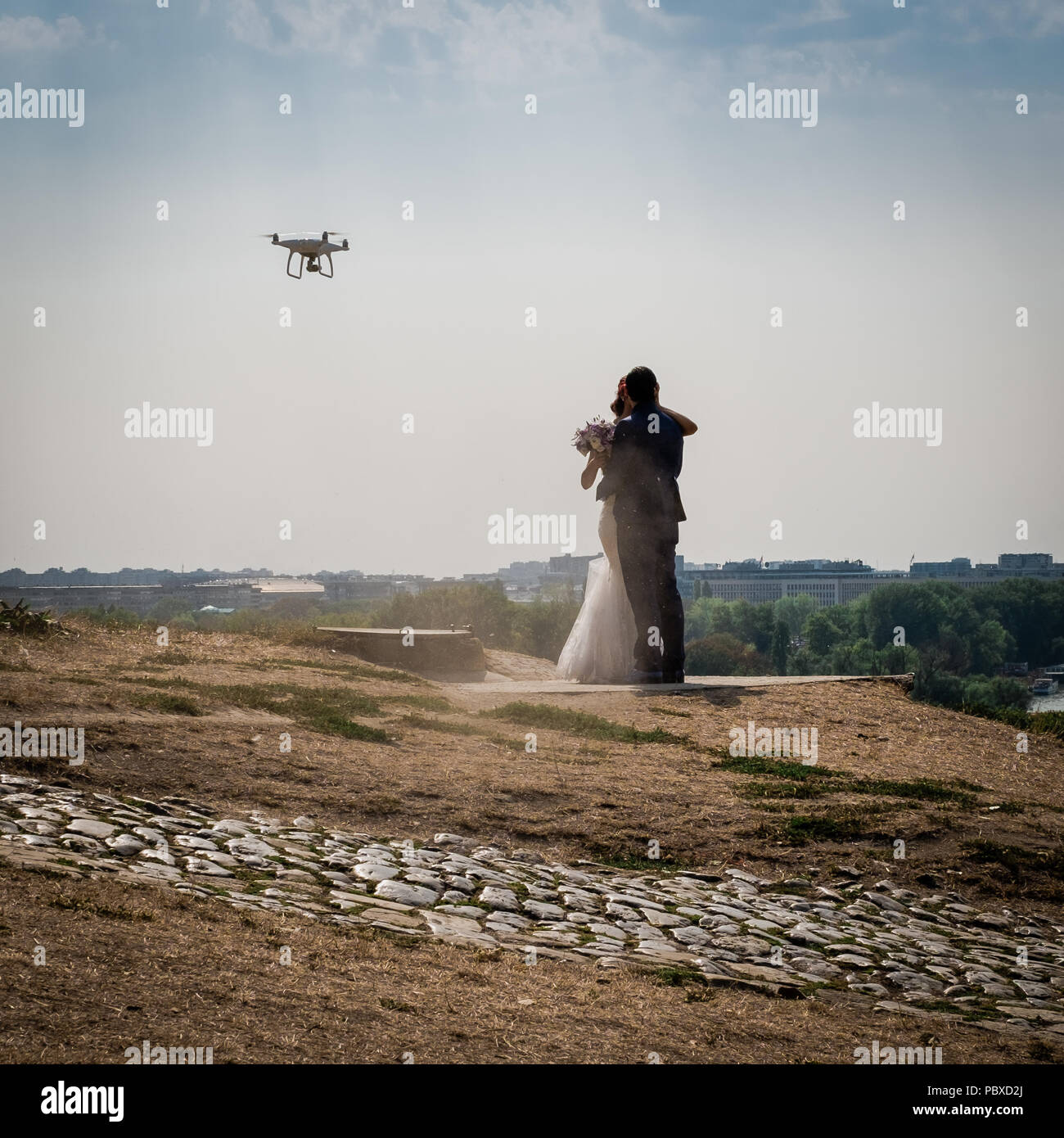 Two newlyweds kissing while a drone takes them. Belgrade on the background Stock Photo