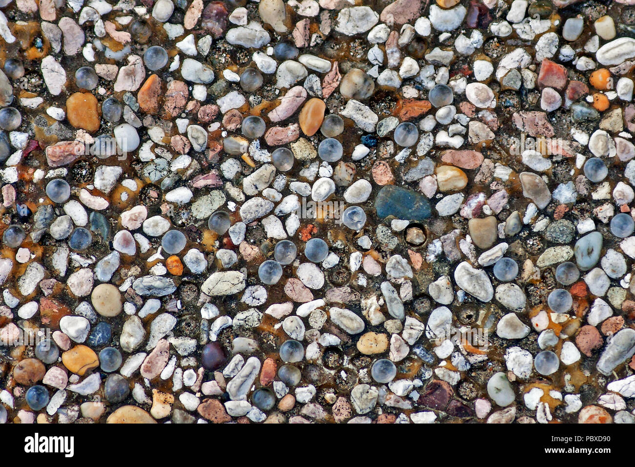 A myriad of small stones and pebbles of different shapes and colours crammed together into a concrete base to form pebble dashing. Stock Photo
