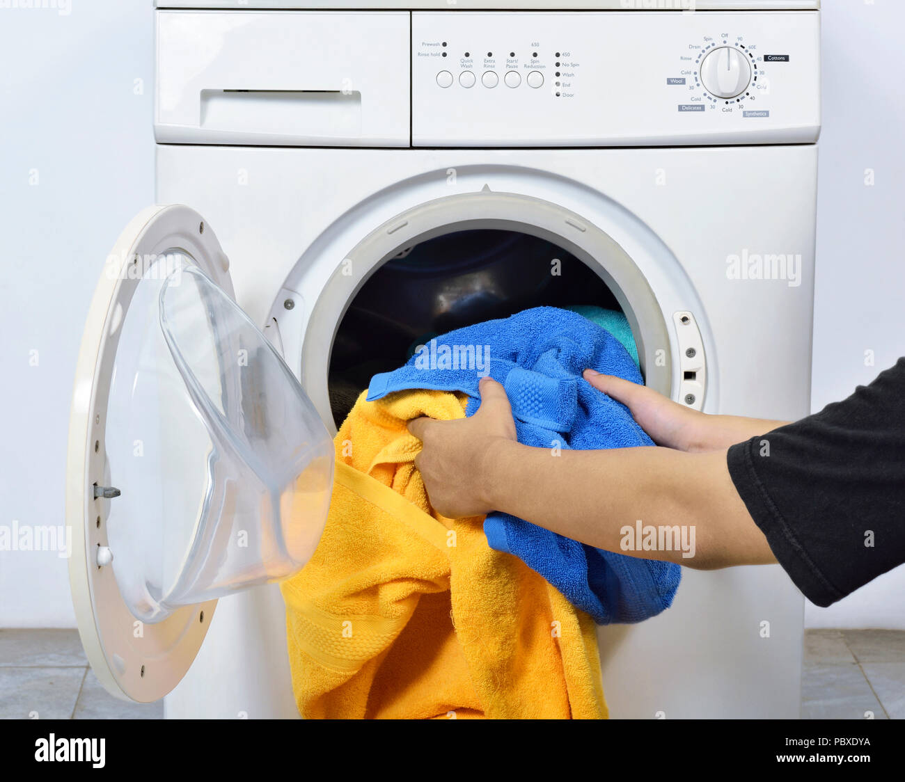 Man loading the dirty towels into washing machine for washed in home Stock Photo