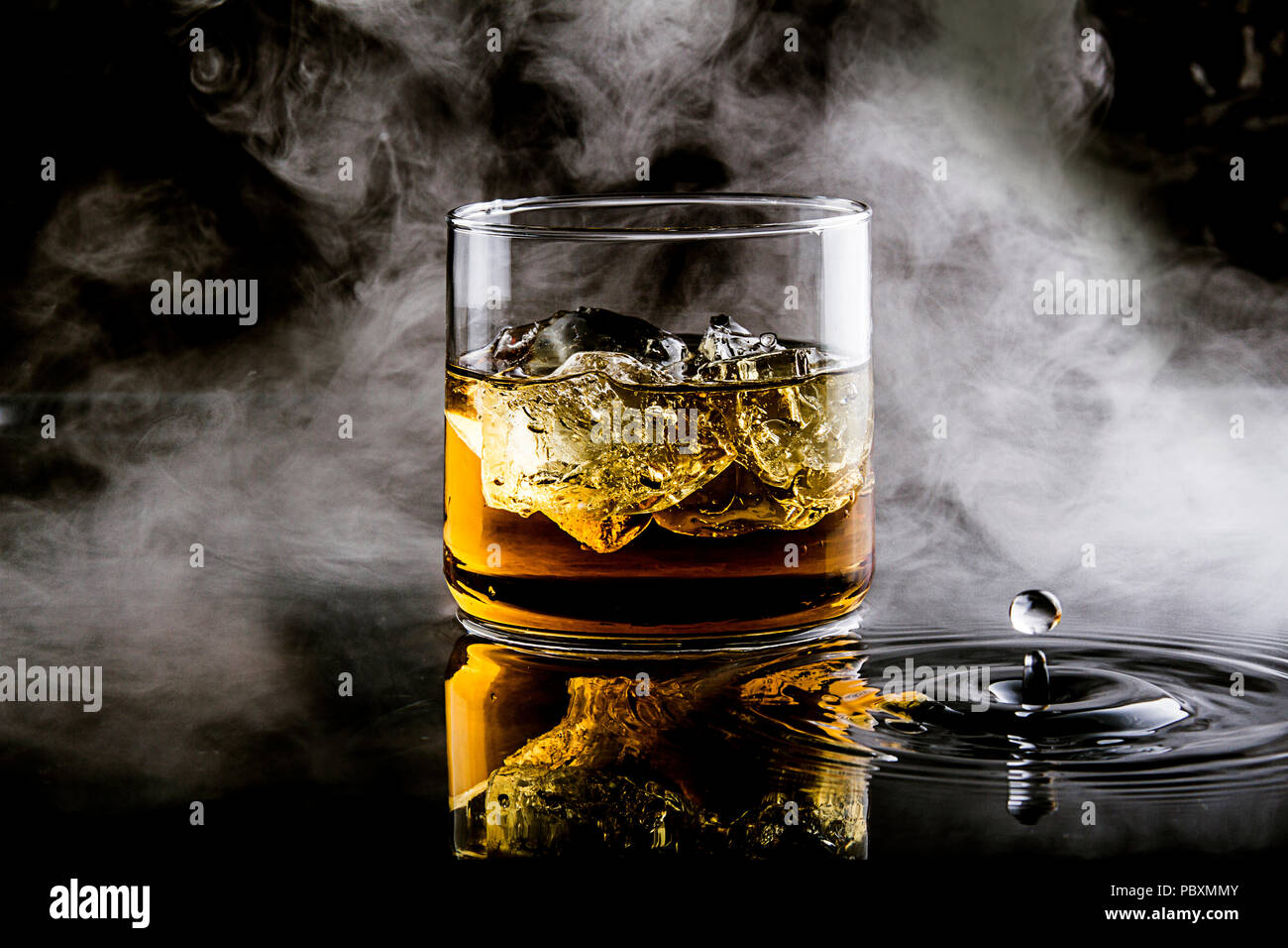 whiskey with ice on black background with splashes of water and smoke