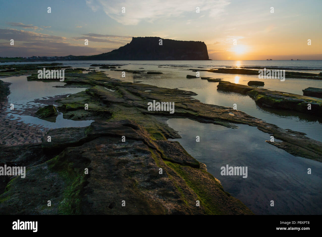 Sunrise at Ilchulbong volcano crater with view over ocean and green moss stones, Seongsan, Jeju Island, South Korea Stock Photo