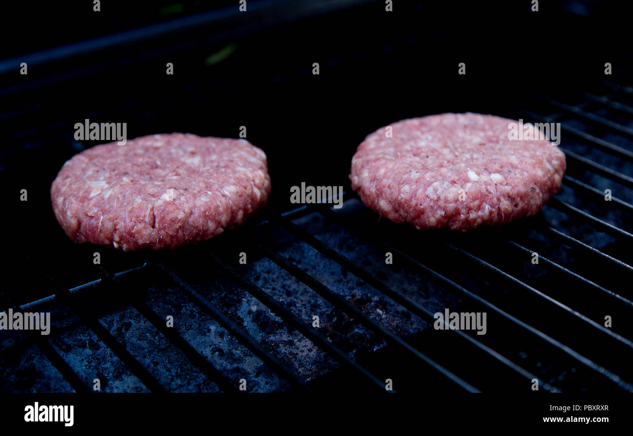 Raw beefburgers about to be cooked on a BBQ Stock Photo