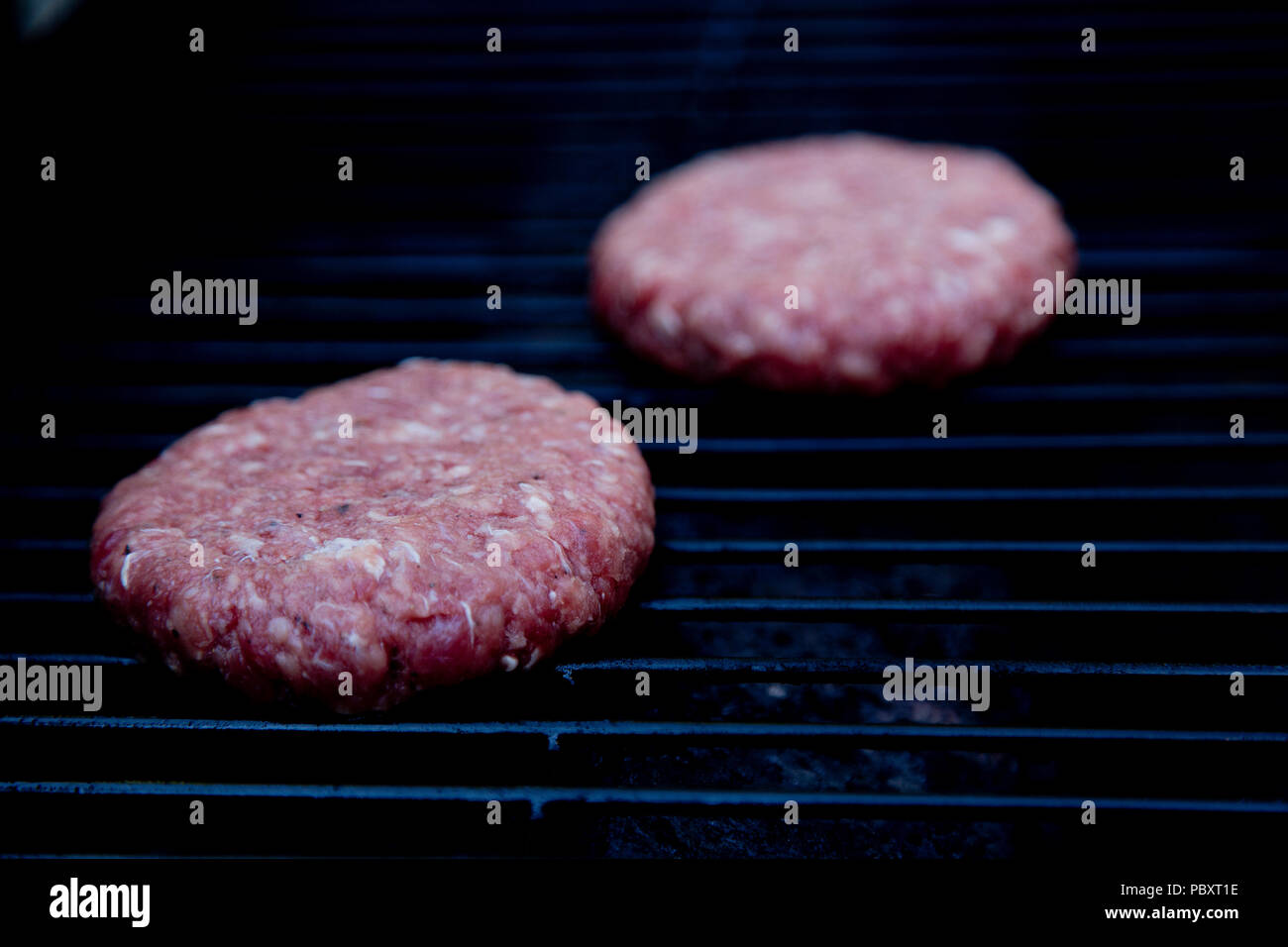 Raw beefburgers about to be cooked on a BBQ Stock Photo