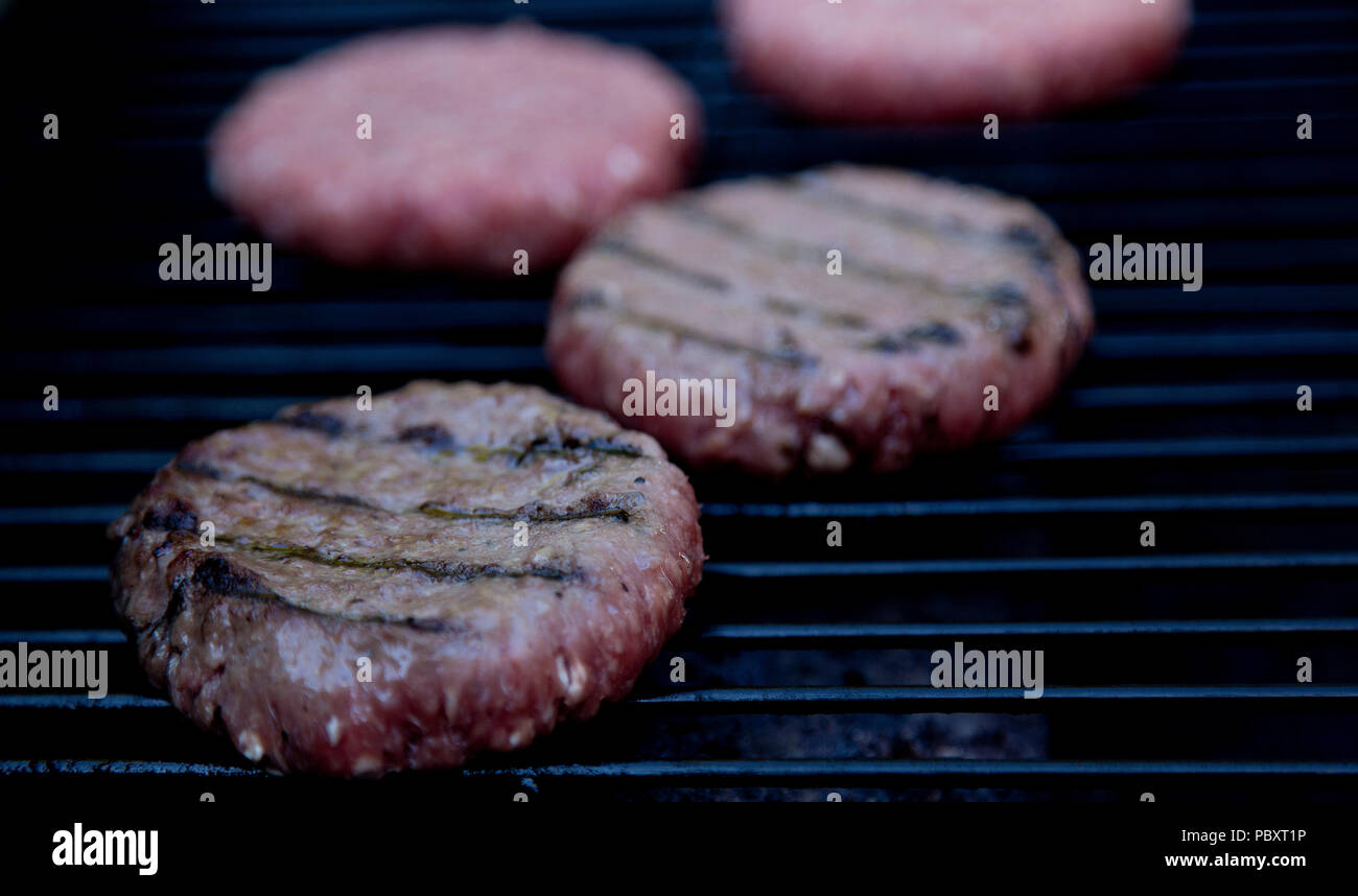beefburgers cooking on BBQ Stock Photo