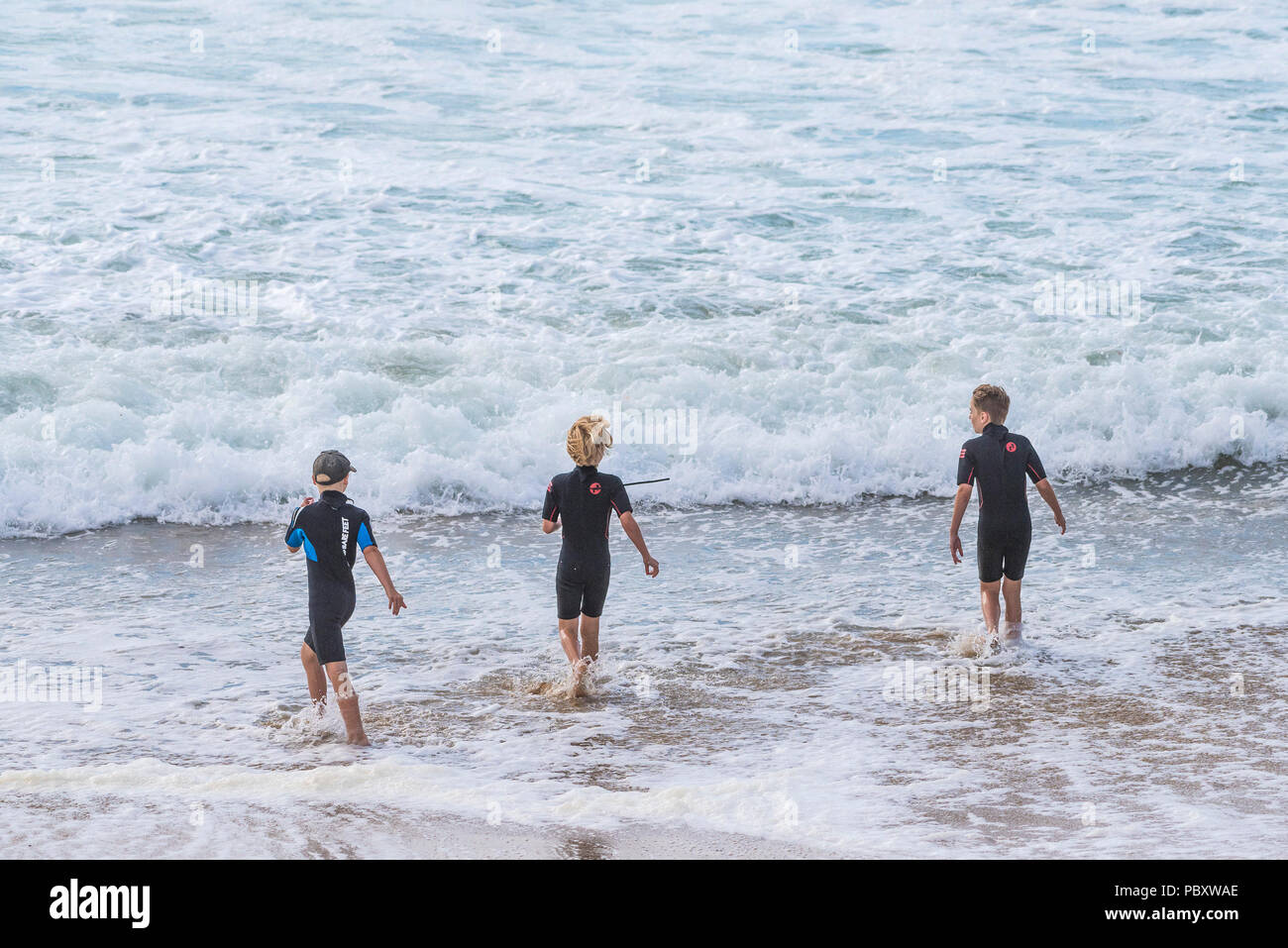 Young boys in wetsuits playing in the sea. Stock Photo