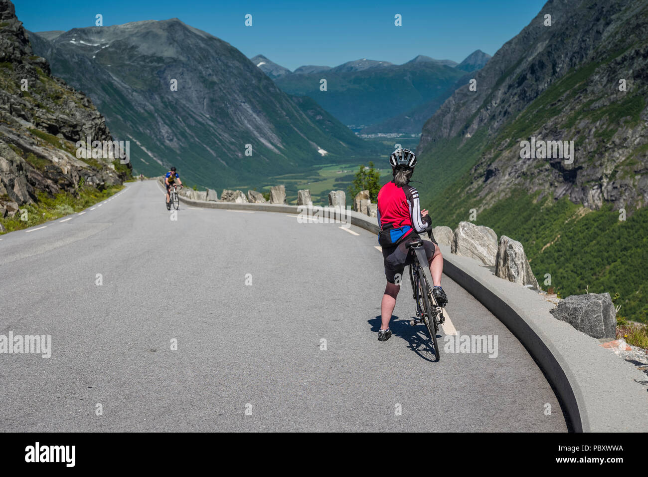 Female cyclist looking at the view on the descent of the famous Trollstigen pass, Norway Stock Photo