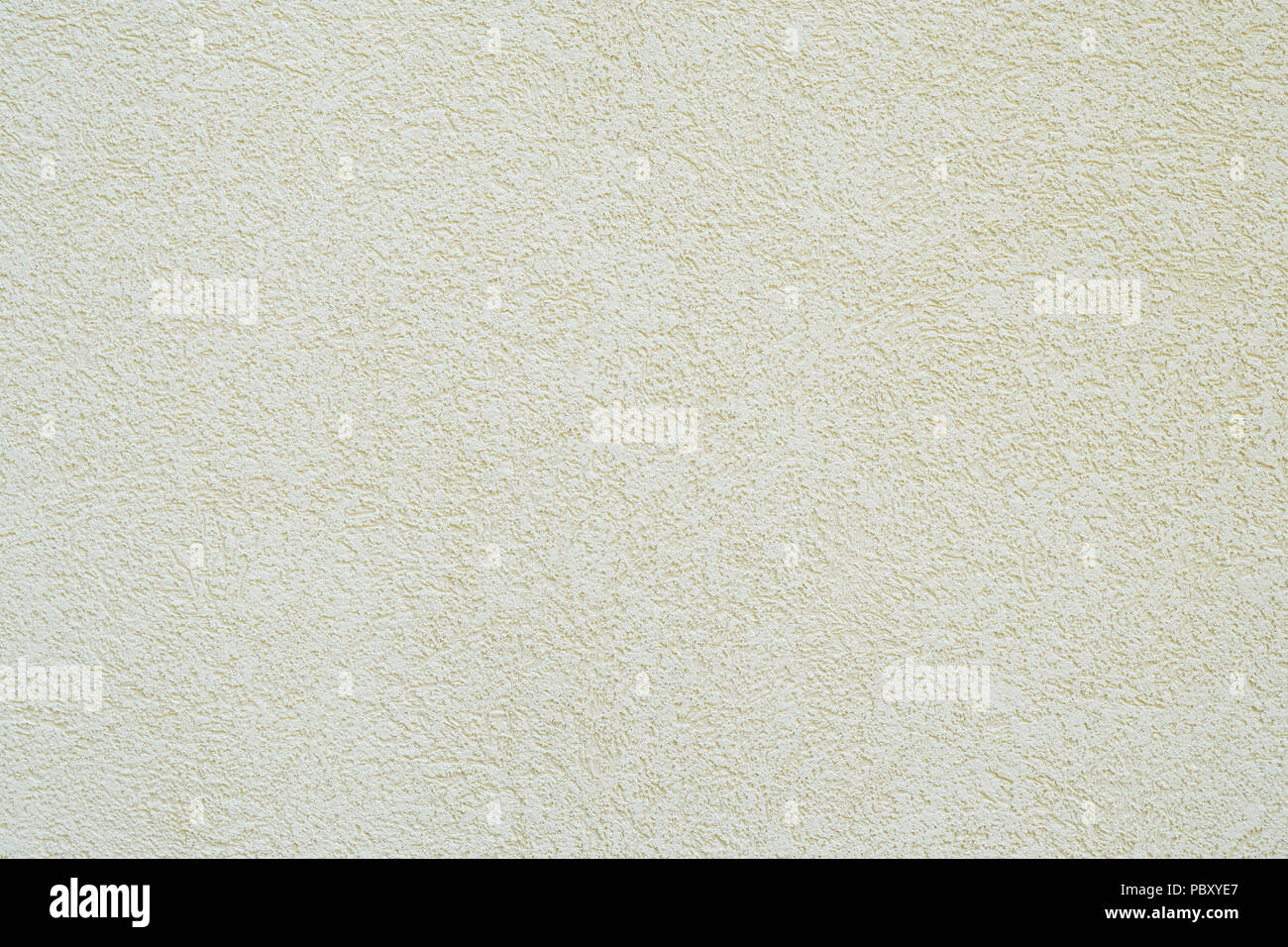 background wall with off-white or pale yellow roughcast plaster texture Stock Photo