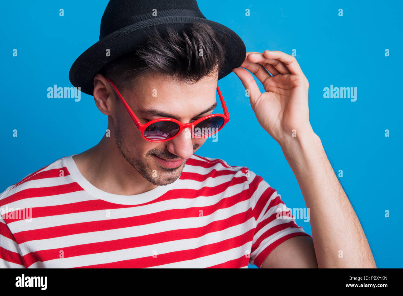 Portrait of a young man in a studio with sunglasses on a blue ...