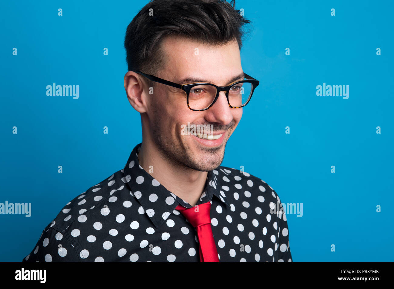 Portrait of a young man with glasses in a studio on a blue background ...