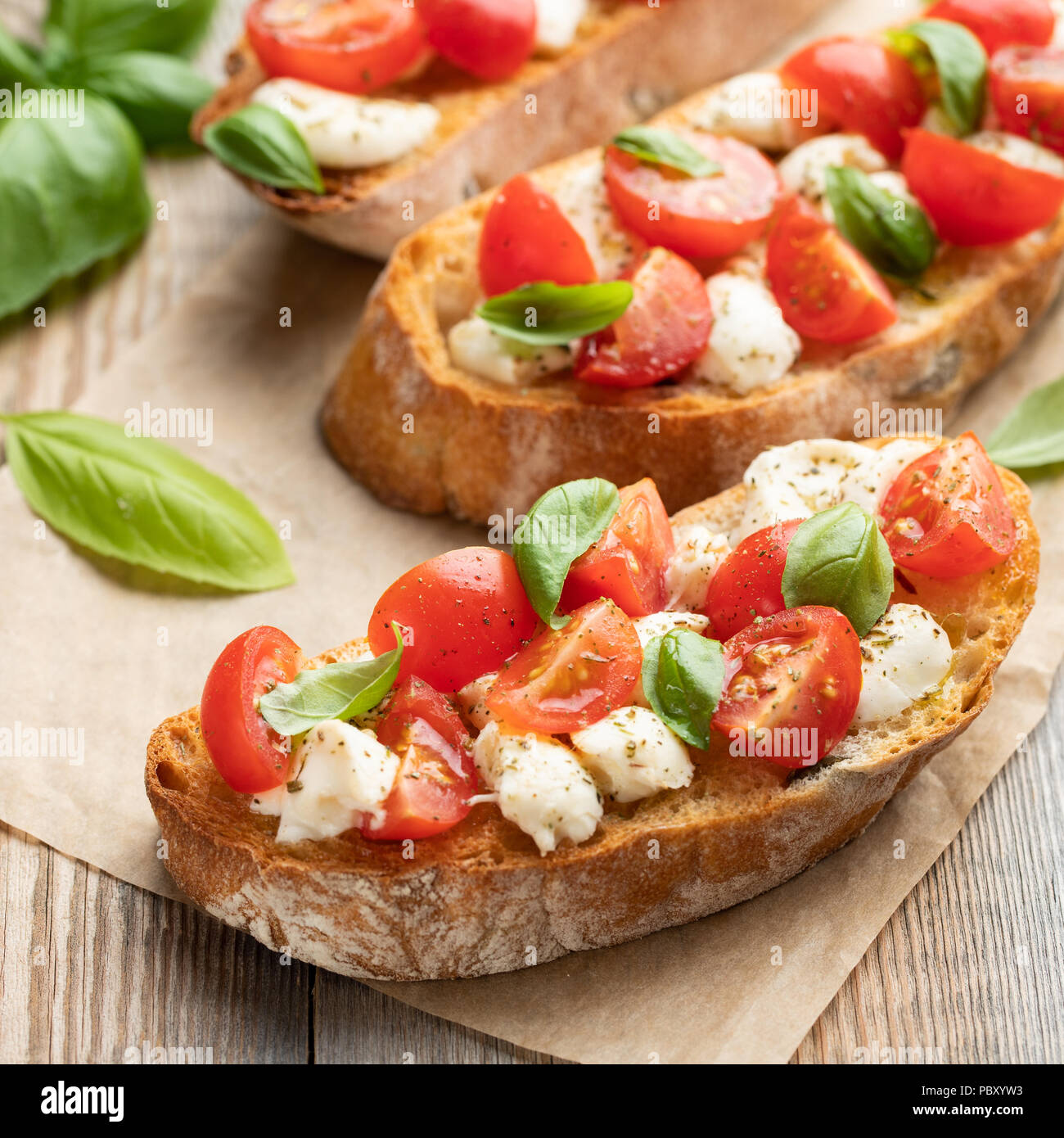 Bruschetta with tomatoes, mozzarella cheese and basil on a old rustic ...