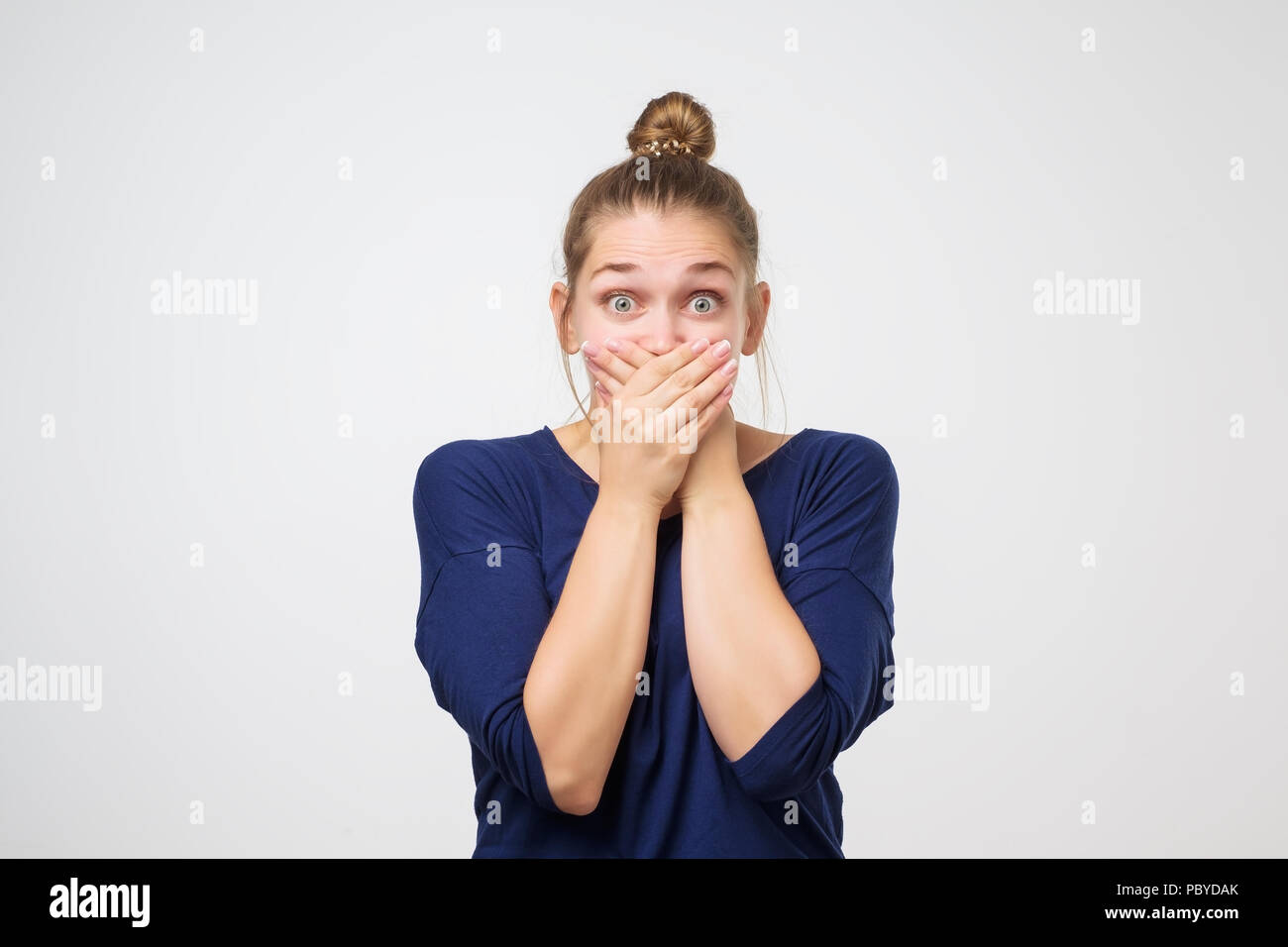 Young woman covering her mouth, isolated on white Stock Photo