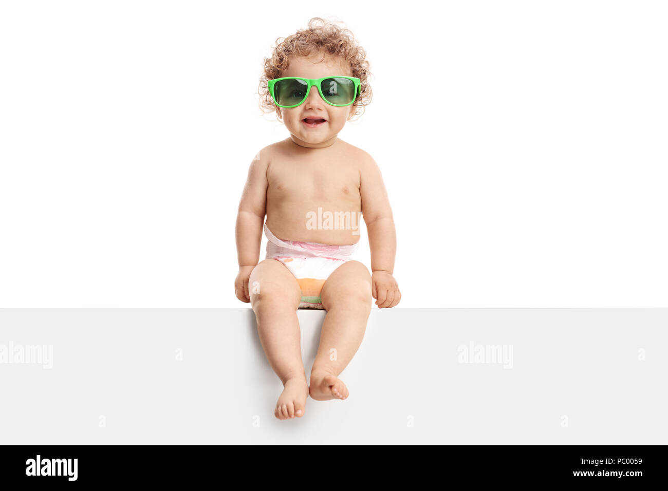 Adorable baby boy with a pair of sunglasses sitting on a panel isolated on white background Stock Photo
