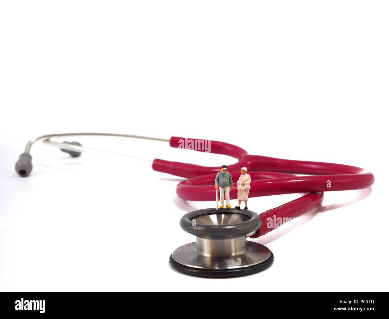 Miniature senior couple, small figures, standing on stethoscope. Health care and healthy lifestyle concept. Stock Photo