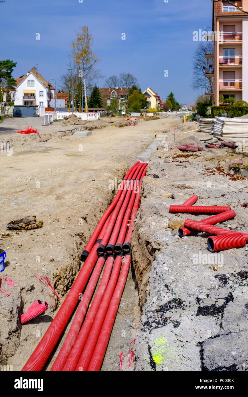 Strasbourg, preliminary tram construction site, line E extension, dirt road, red power pipes and outlets, trench, houses, Alsace, France, Europe, Stock Photo