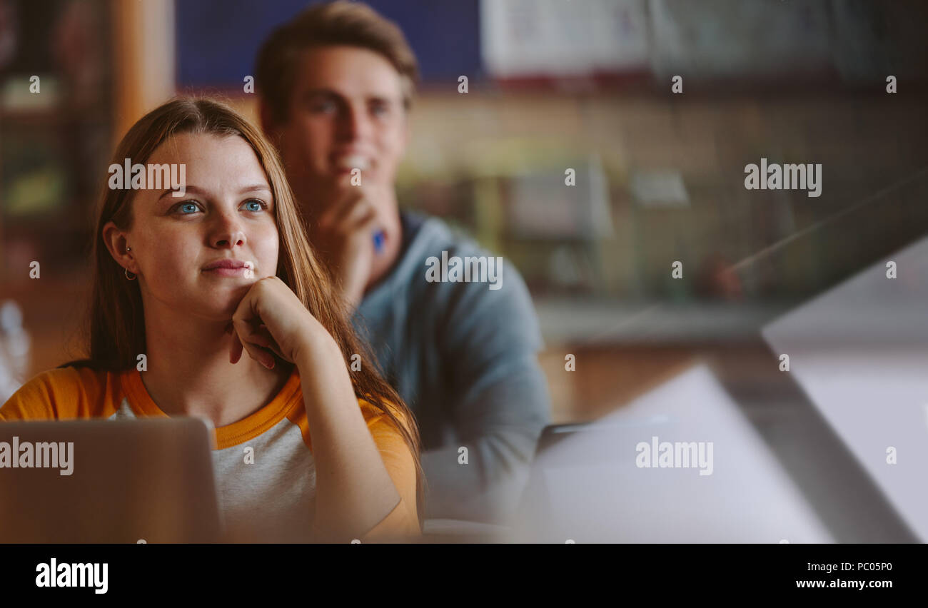 Pretty teenage student paying attention to lecture in classroom. Woman studying at the college classroom. Stock Photo