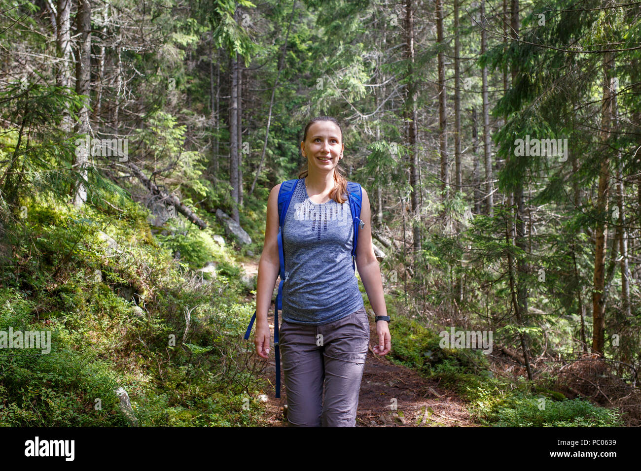 Young smiling woman with backpack hiking in forest Stock Photo