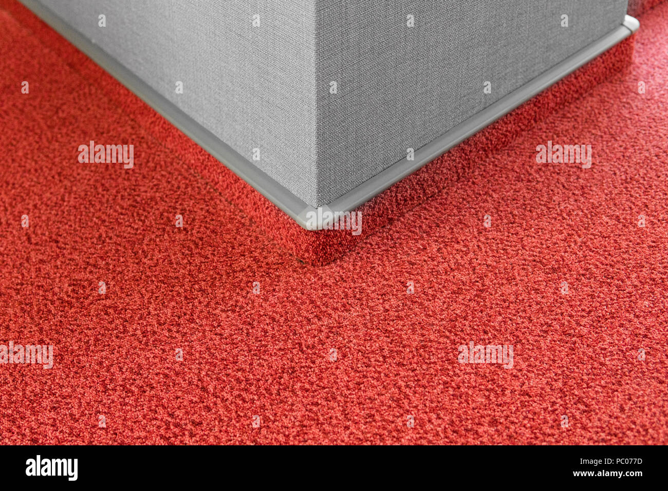 Carpet floor with a carpet baseboard on a grey wall. Stock Photo
