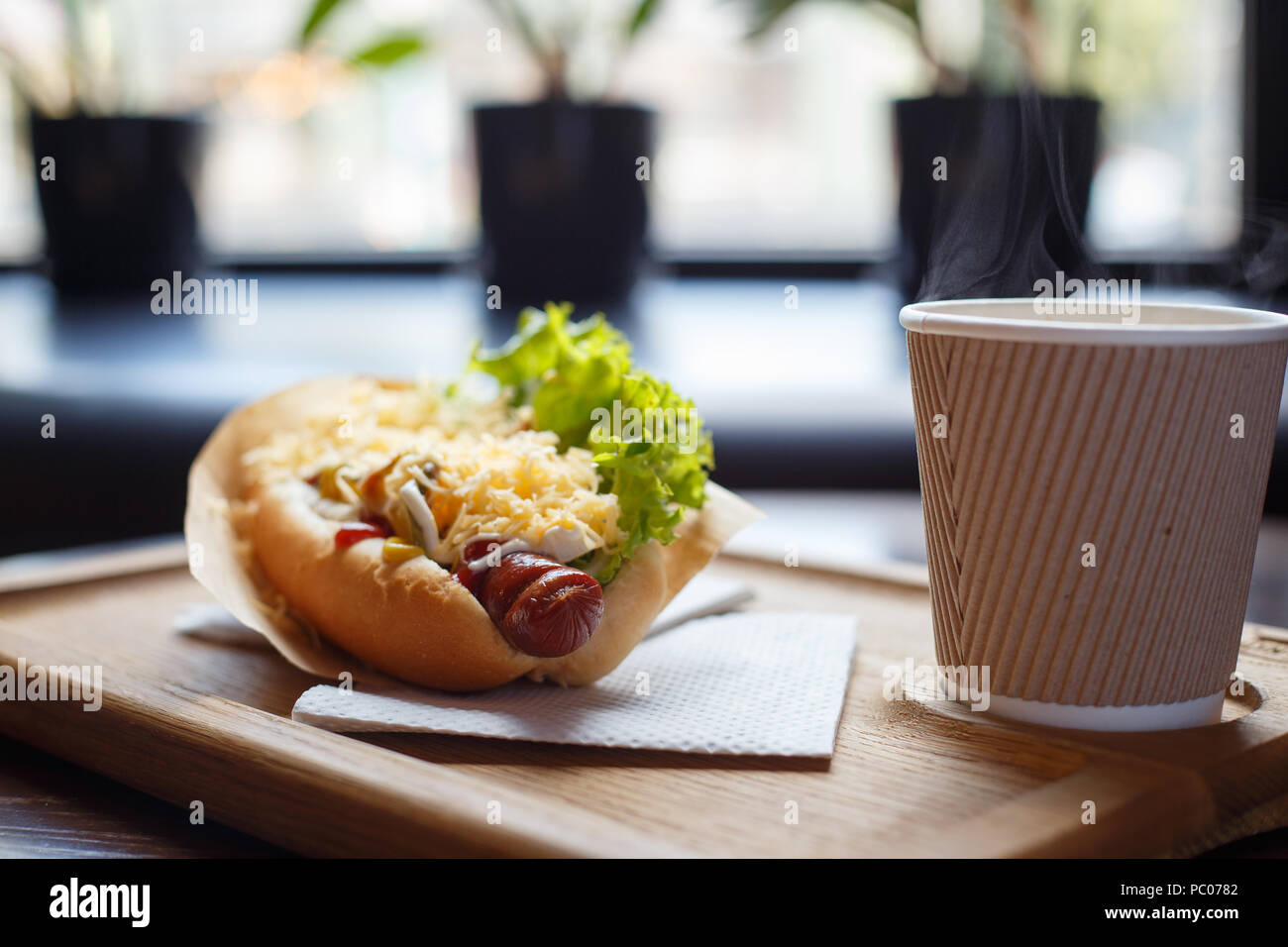 Hot dog with salad and cup of coffee on the table Stock Photo