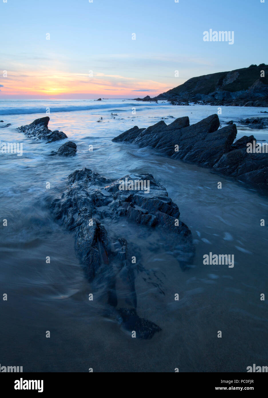 Sun setting over Dollar Cove at Gunwalloe in Cornwall Stock Photo