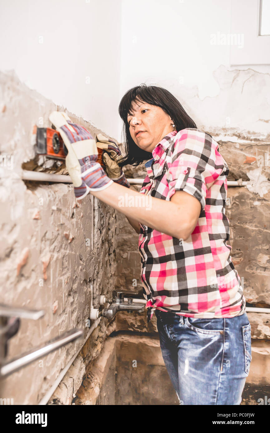 Clever woman repairing her bathroom sink pipe with positive attitude