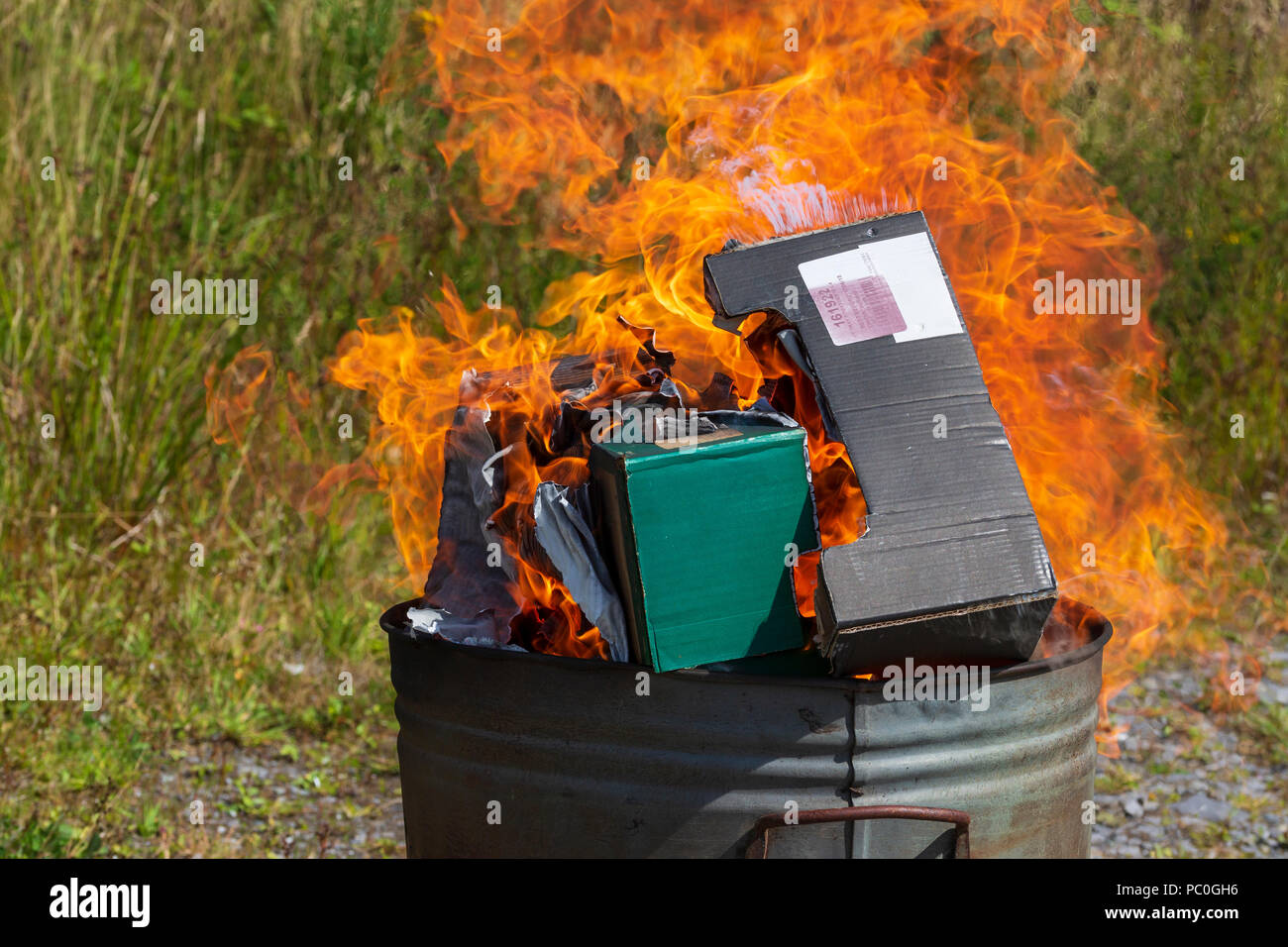 Burning waste paper and cardboard in small garden incinerator Stock Photo