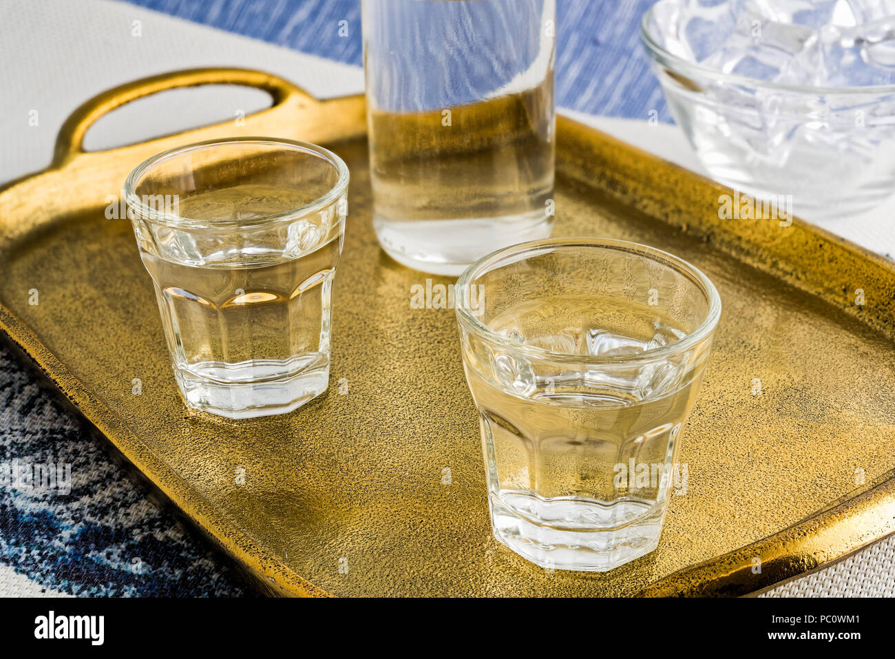 Glasses and bottle of traditional drink Ouzo or Raki on bronze dish