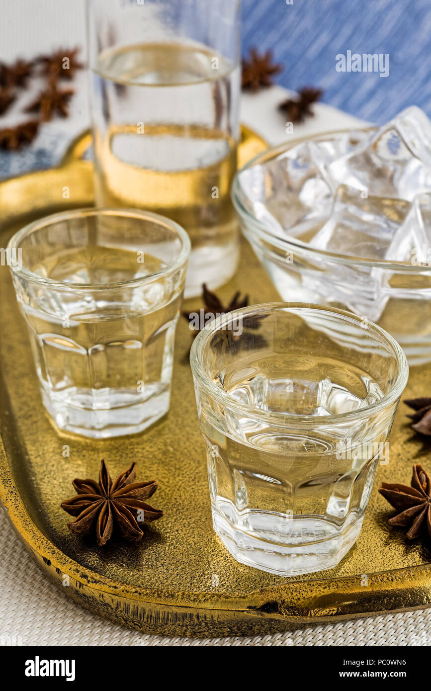 Glasses and bottle of traditional drink Ouzo or Raki on bronze dish