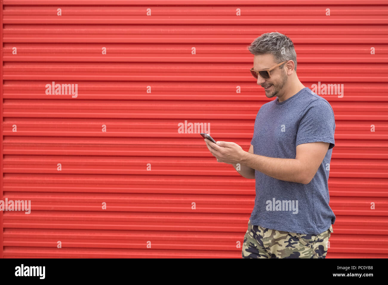 Modern man using smartphone against red background. Space for copy. Stock Photo