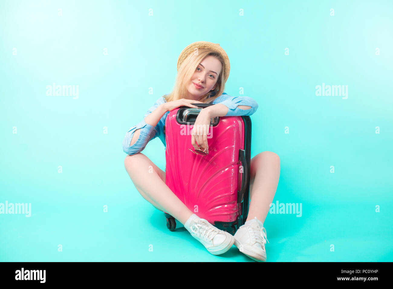 woman sitting behind the suit case. full length portrait.copy space. happy travelling.itchy feet Stock Photo