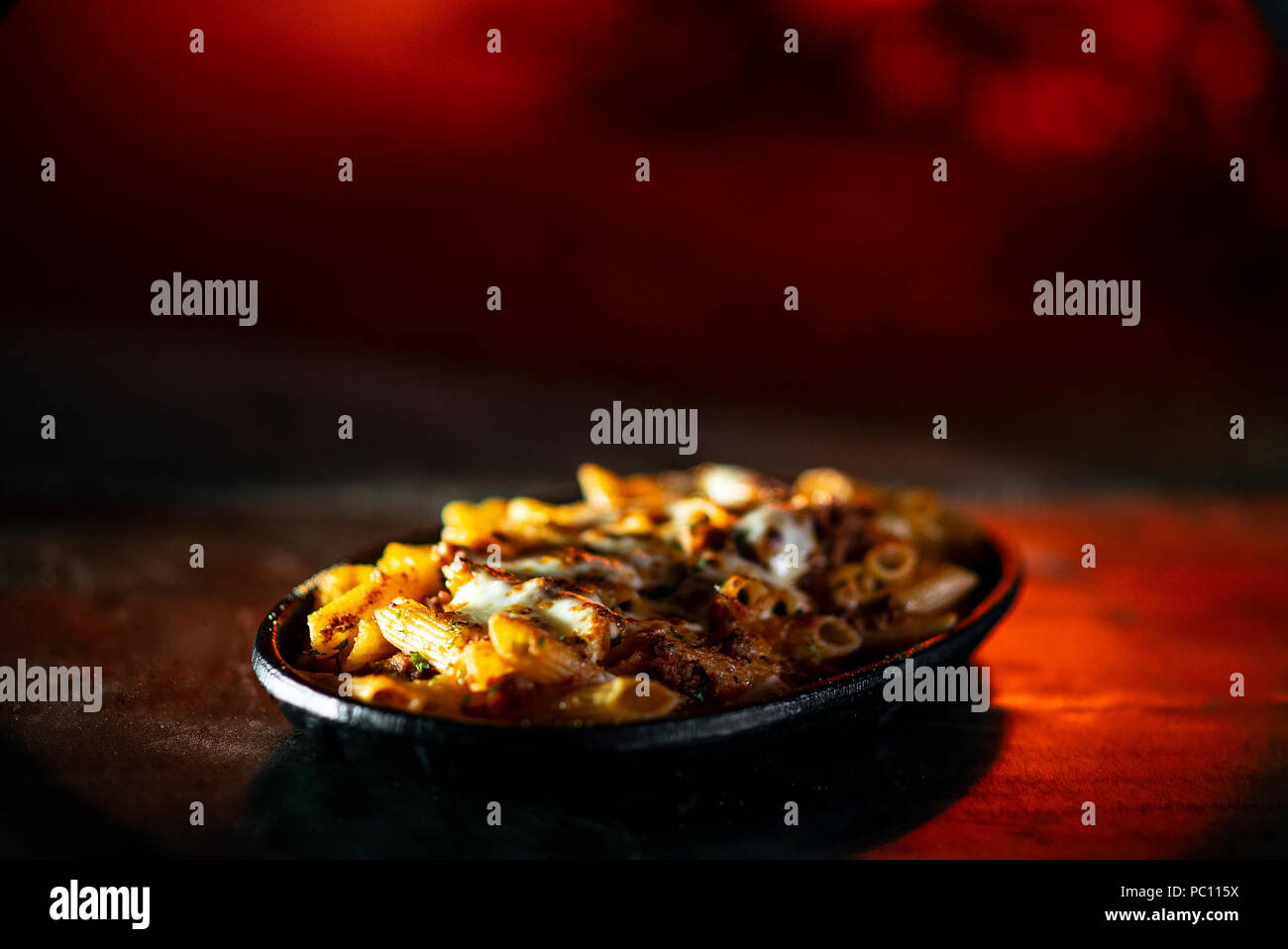 gourmet wood fired oven baked fresh pasta penne bolognese and mozzarella cheese dish Stock Photo