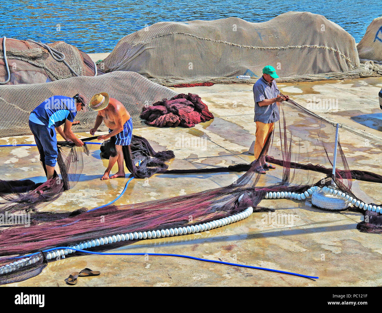 Fishermen mending nets at Javea Marina, Costa Blanca, Spain Stock Photo
