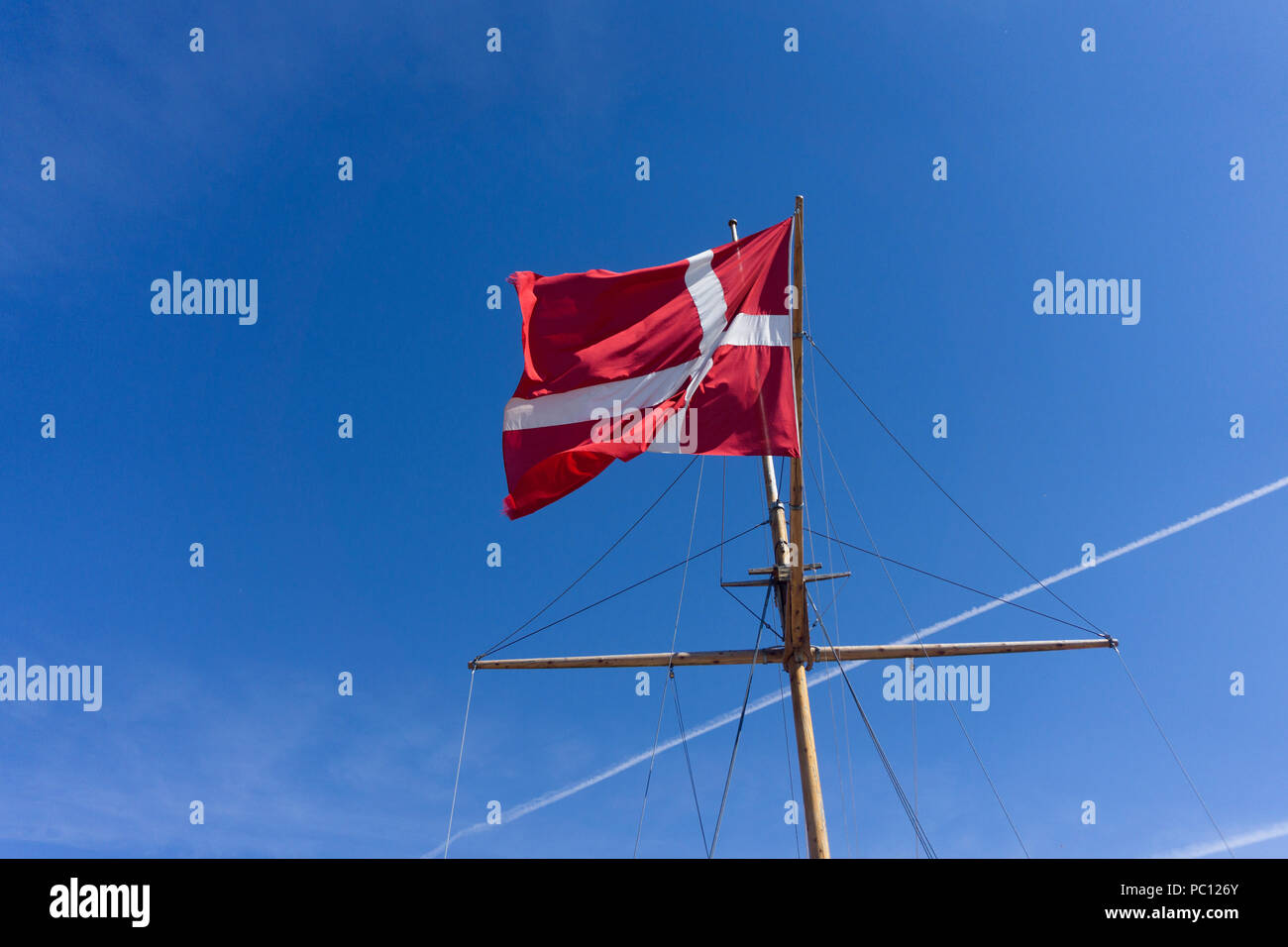 Denmark flag on a ship mast waivng against a clear blue sky Stock Photo