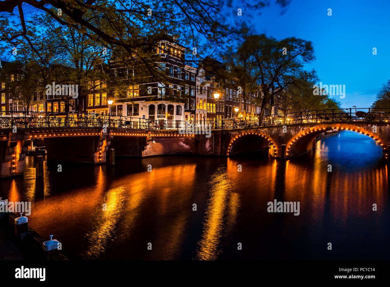 Night view with bridge, bicycles and water reflection in Amsterdam city, Netherlands Stock Photo